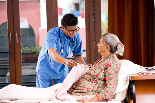 Male nurse home caregiver helping senior woman relaxing on bed